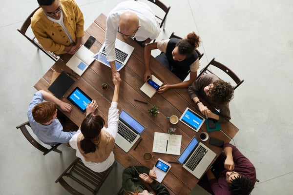 People around a meeting table, business partners shaking hands