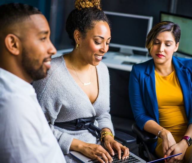 Three people collaborating around a laptop