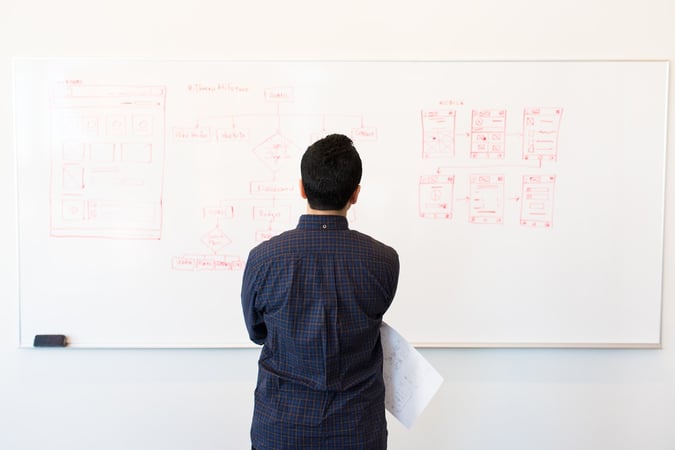 man looking at whiteboard with app design-2