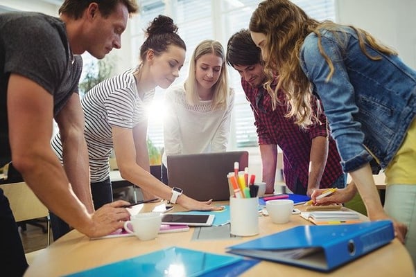 Group of people discussing around a laptop